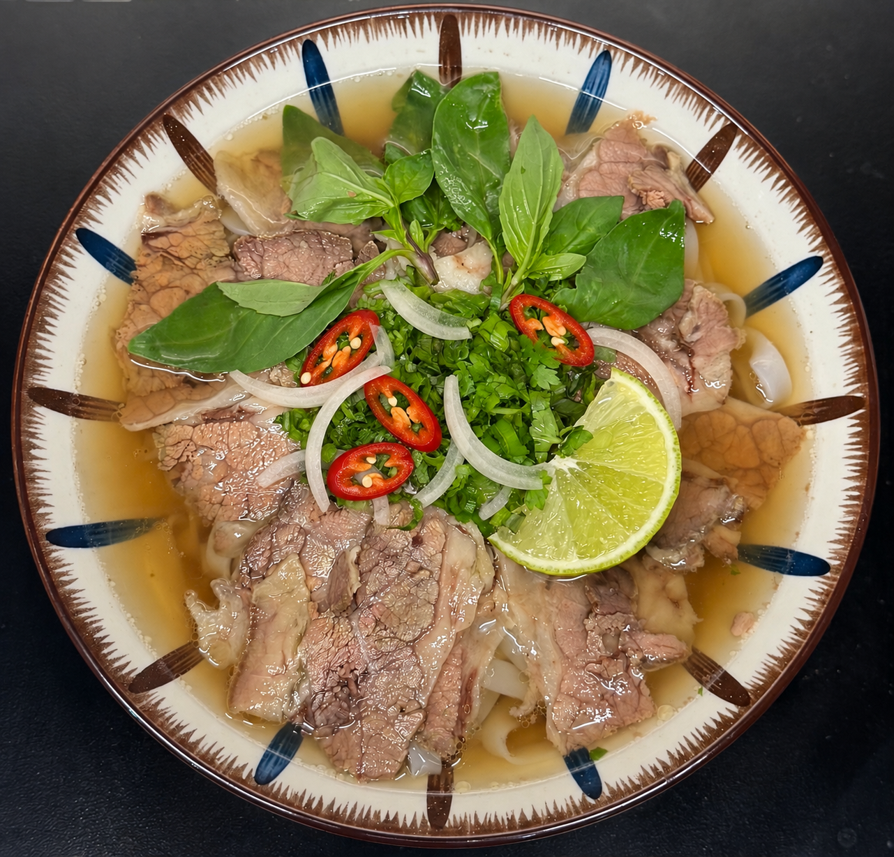 Beef phở topped with sliced red chilli, onion, fresh herbs and lime